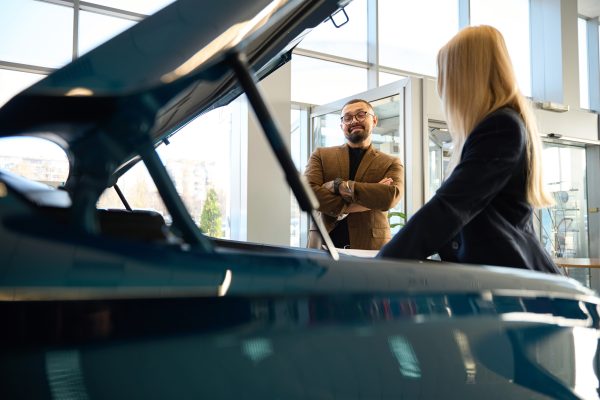 Man with a beard and glasses looks into the hood of the car he wants to buy